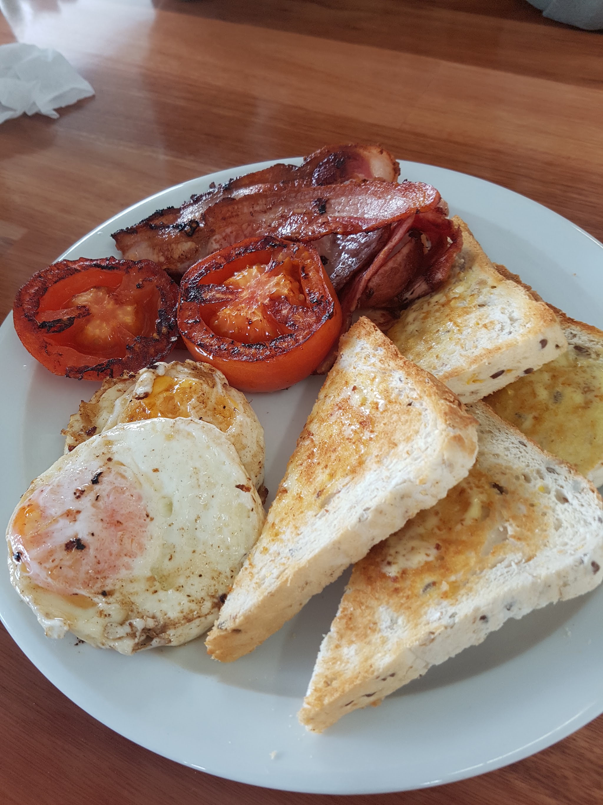 Cooked breakfast with bacon, fried egg, grilled tomato and toast